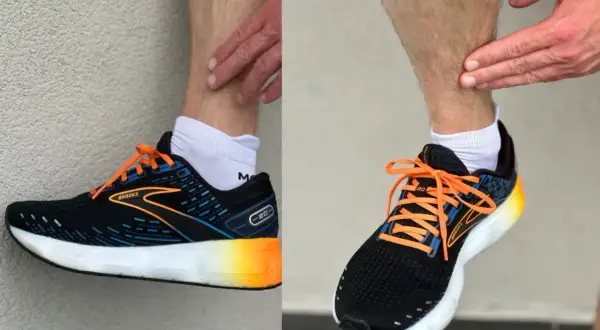 Biegacz pokazuje ból w łydce, który może być objawem shin splints. Na nogach ma czarne buty sportowe Brooks z pomarańczowymi sznurówkami.