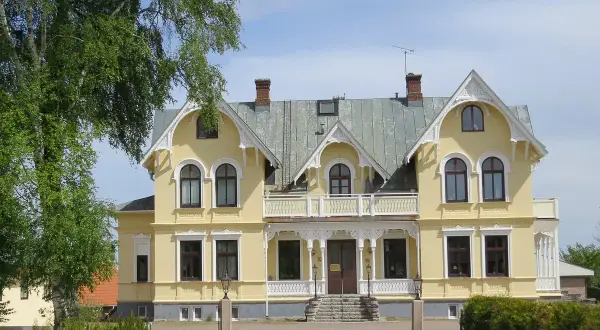 Gult hus med vita detaljer, en vacker entré och grönska. Perfekt för en Scandic Billingen frukost.