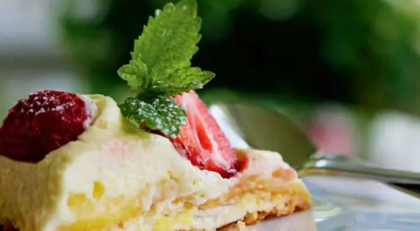 En bit pavlova med lemoncurd, toppad med färska jordgubbar och mynta. En härlig sommardessert.