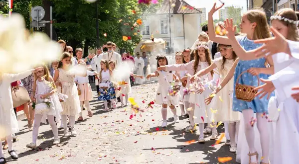 15 czerwca. Dzieci w białych strojach sypią kwiaty podczas procesji. W tle widać duchownych i wiernych.