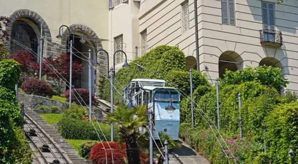 Bergamo kolejka wjeżdża po stromych torach wśród zieleni i zabytkowych budynków.