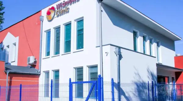 Nowoczesny budynek kliniki medycznej "Wiśniowa Clinic" z niebieskim ogrodzeniem.