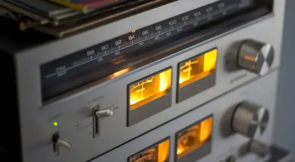 Klasy wzmacniaczy w retro sprzęcie audio. Wskaźniki VU świecą na pomarańczowo, a tuner pokazuje częstotliwość 94 MHz.