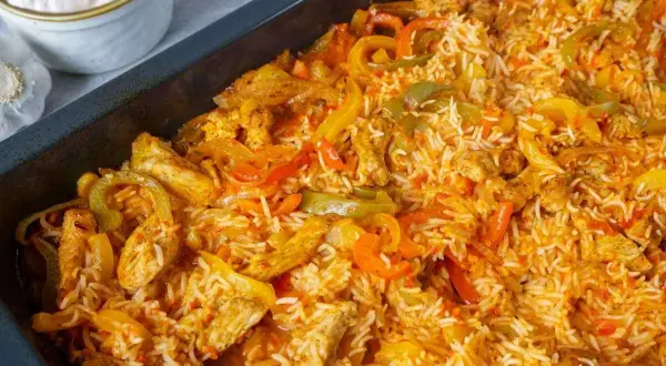 Reis im Backofen mit Hähnchenstreifen und bunten Paprikastreifen. Eine köstliche Mahlzeit, die im Ofen zubereitet wird.