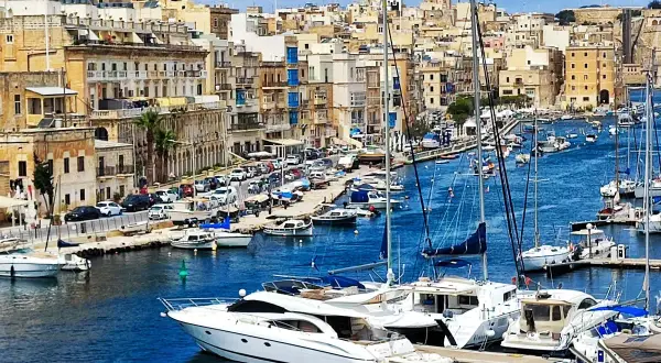 Malta historia: malowniczy port pełen jachtów, z zabytkową zabudową w tle.
