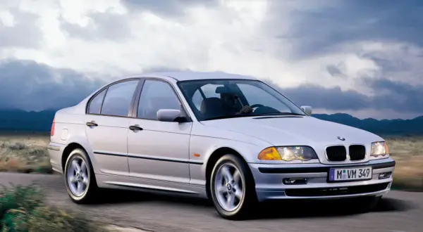 Un BMW 320d E46 150cv Stage 2 plateado circula por una carretera rural.