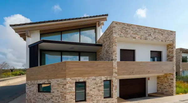 Casa moderna con revestimiento de piedra y madera, ideal para quienes buscan cómo revestir una pared exterior con estilo y durabilidad.