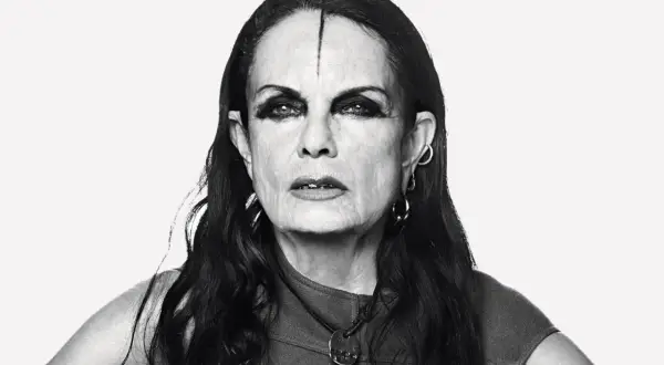 Black and white portrait of Michèle Lamy with dramatic eye makeup and a line drawn on her forehead.