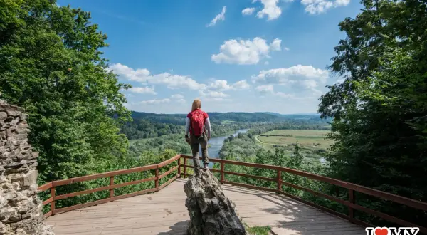 Kobieta z plecakiem podziwia widok na dolinę rzeki. Idealne miejsce, by zastanowić się, gdzie w Bieszczady wybrać się na wędrówkę.