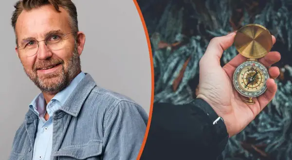 Man med glasögon och kompass i handen, symbol för att navigera i en VUCA-värld.