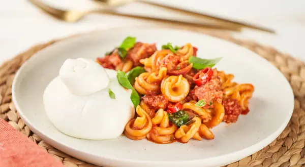 Pasta mit Salsiccia-Sauce und Burrata auf einem Teller.