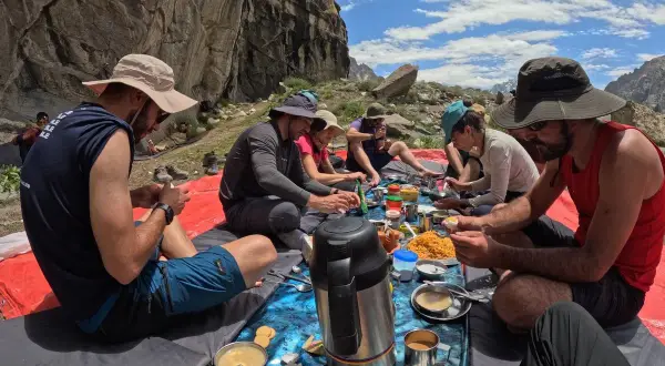 Grupa ludzi podczas posiłku na świeżym powietrzu, przygotowująca się do trekkingu pod K2.