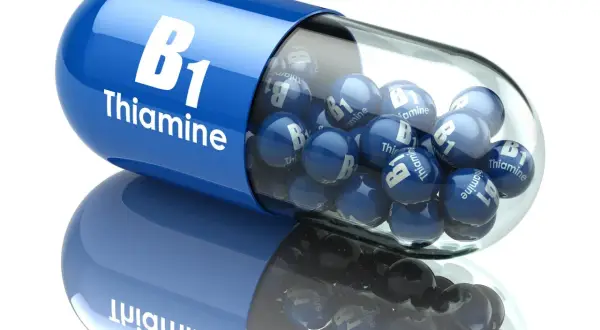 Niebieska kapsułka wypełniona małymi kulkami z napisem "B1 Thiamine". Witamina B1 dla zdrowia.