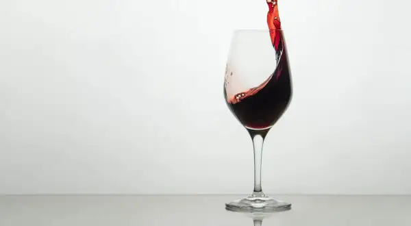 Ein Glas Rotwein mit einer dynamischen Welle, die die Frage aufwirft, wie schmeckt wein.