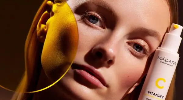 Strahlende Haut dank Vitamin C Skin Care. Eine Frau hält eine Flasche MÁDARA Illuminating Recovery Cream.