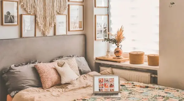 Przytulna sypialnia w stylu boho z łóżkiem, makramą na ścianie i laptopem.