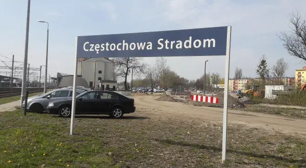 Tablica z napisem Częstochowa Stradom. W tle budynki, tory kolejowe i samochody.
