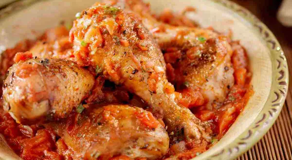 Pollo alla cacciatora ricetta della nonna: succulenti pezzi di pollo in un ricco sugo di pomodoro e erbe aromatiche, serviti in una ciotola rustica.