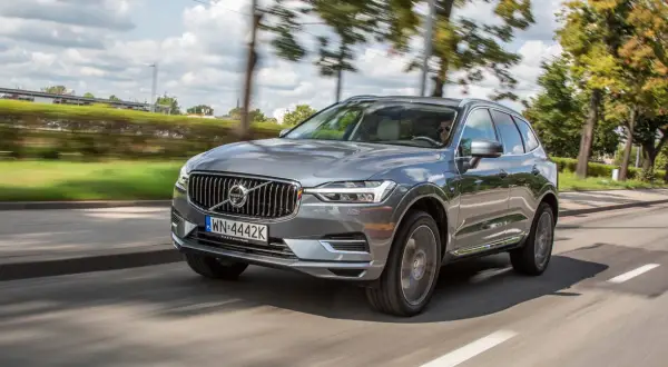 Szary Volvo XC60 T8 w ruchu, z rozmytym tłem drzew i nieba.