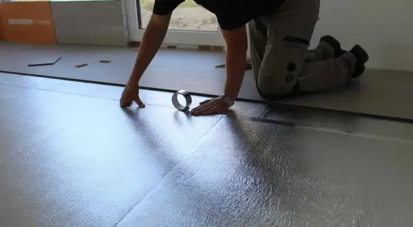 Instalando la mejor base aislante para suelo laminado. Se coloca una lámina plateada reflectante, asegurando un aislamiento térmico y acústico óptimo.