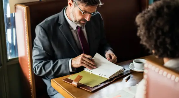 Biznesmen w garniturze przegląda notatki, planując swoje finanse. Może szukać informacji o **novum pozyczki online**.