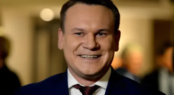 Uśmiechnięty mężczyzna w garniturze, z krawatem. Czy Tarczyński jest żonaty? To pytanie, na które odpowiedź może być ukryta w jego spojrzeniu.