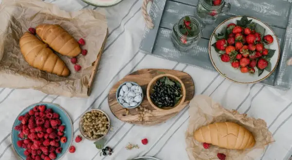 Letnie owoce i rogaliki na pikniku. Idealne na fit przepisy. Truskawki, maliny, porzeczki, arbuzy i napoje z miętą.