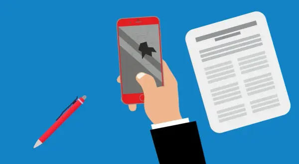 Rękojmia a gwarancja: ręka trzyma pęknięty telefon, obok dokument i długopis.