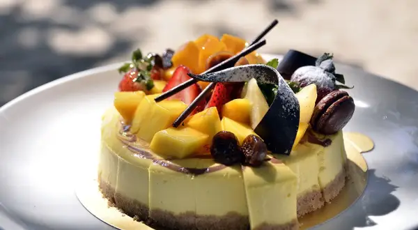 Kolorowe ciasto z mango, truskawkami i figami na talerzu. Jak ułożyć ciasto na talerzu, by wyglądało apetycznie?