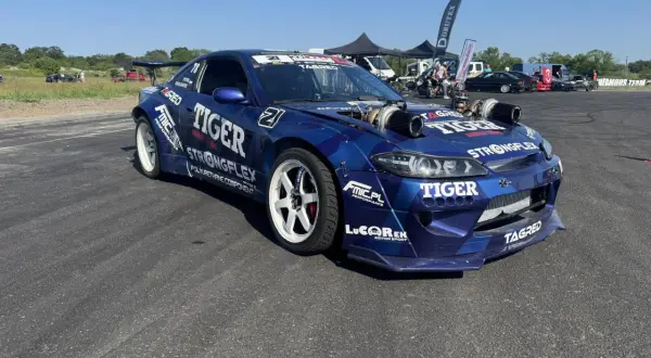 Niebieski samochód driftowy s15 z podwójnymi turbosprężarkami i licznymi sponsorami, gotowy do akcji.