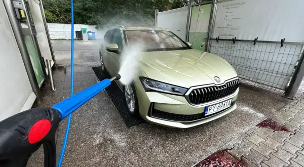 Usuwanie żywicy z lakieru: mycie auta na myjni bezdotykowej. Woda pod ciśnieniem spływa po masce.