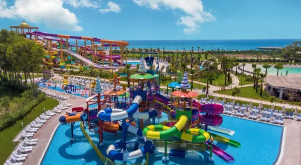 Kolorowy aquapark z mnóstwem zjeżdżalni i basenów, idealny na wakacje all inclusive w Turcji.