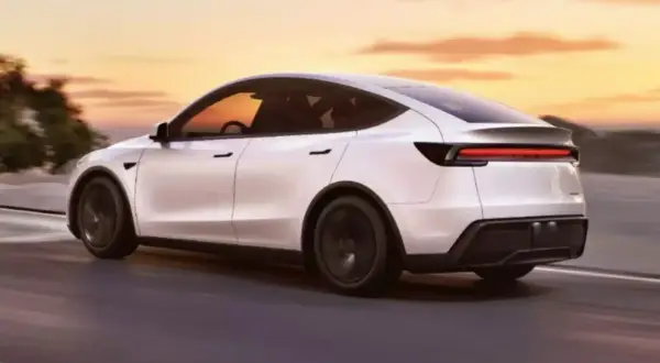 Biała Tesla Model Y jedzie po drodze o zachodzie słońca. Zastanawiasz się, ile waży Tesla Model Y?