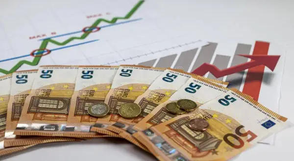 Euro banknoty i monety na tle wykresów wzrostu. Symbolizują inwestycje, zyski i potencjalną subwencję.