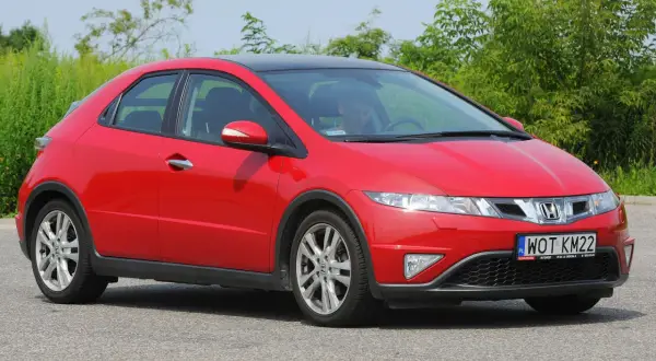 Czerwony Honda Civic 8 z czarnym dachem, zaparkowany na drodze. Widać przednie światła i grill.