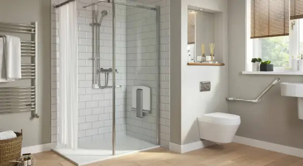 Salle de bain moderne avec douche de sol, carrelage blanc, porte-serviettes chauffant et WC suspendu avec barres d'appui.