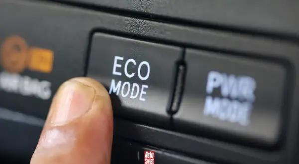 Palec naciska przycisk "ECO MODE", pytając "econ co to?". Obok przycisk "PWR MODE".