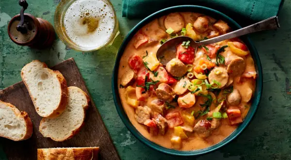 Herzhaftes Wurstgulasch mit Paprika und Tomaten, serviert mit frischem Brot und einem kühlen Bier. Ein tolles Rezept für gemütliche Abende.