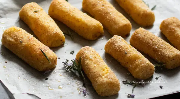 Crocchette di patate al forno dorate e croccanti, pronte per essere gustate. Profumate con rosmarino fresco.