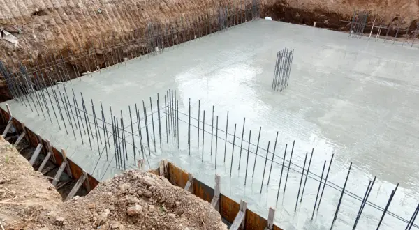 Świeżo wylany beton na fundamenty, zbrojenie gotowe do dalszych prac. To kluczowy etap, by wiedzieć, jak wyliczyć beton na fundamenty.
