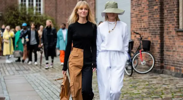 Deux femmes marchent, l'une porte un pantalon bicolore audacieux, l'autre un ensemble blanc décontracté.