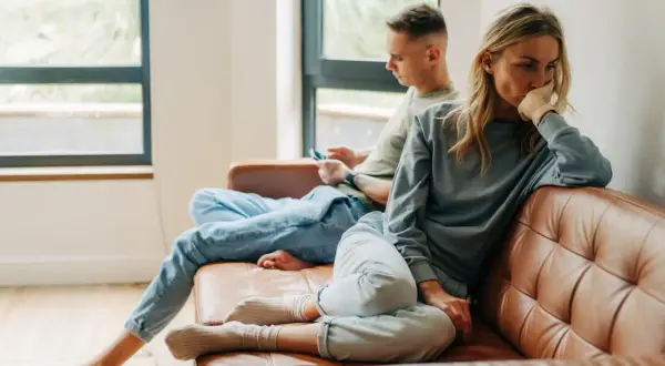 Een vrouw denkt diep na, terwijl een man op zijn telefoon kijkt. Het lijkt erop dat opposites attract betekenis hier niet opgaat.