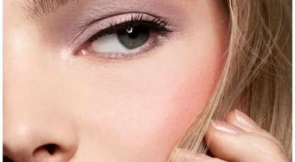 Un occhio truccato con ombretto rosa e un tocco di blush sulle guance, che dona un aspetto sano e radioso.
