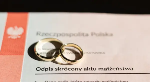 Złote obrączki na odpisie skróconym aktu małżeństwa, symbolizujące związek.