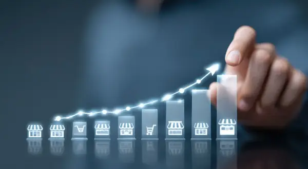 Wykres wzrostu z ikonami sklepów i koszyka, symbolizujący strategię cross selling i rozwój biznesu.