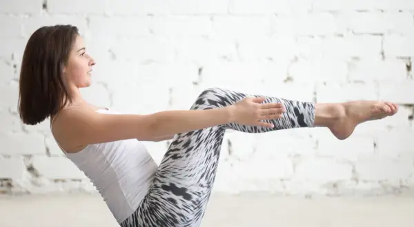 Kobieta ćwiczy pilates przy ścianie, wzmacniając mięśnie brzucha.