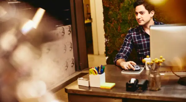 Uomo al computer, con sfondo di muschio. Potrebbe essere un annuncio per un job posting interno.