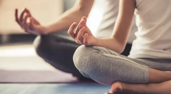 Zwei Personen in entspannter Haltung, Hände in Mudras. Eine friedliche Szene, die Entspannungstechniken bei Stress zeigt.