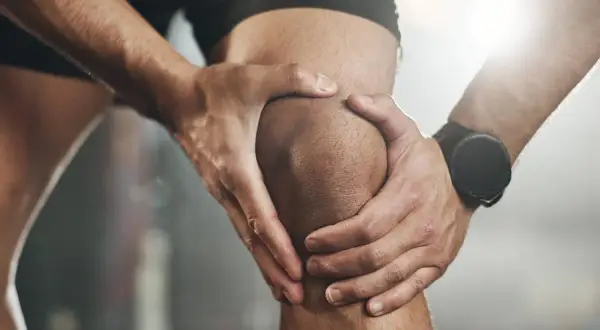 Sportler hält schmerzendes Knie. Möglicher Kreuzbandriss? Ein Selbsttest kann erste Hinweise geben.