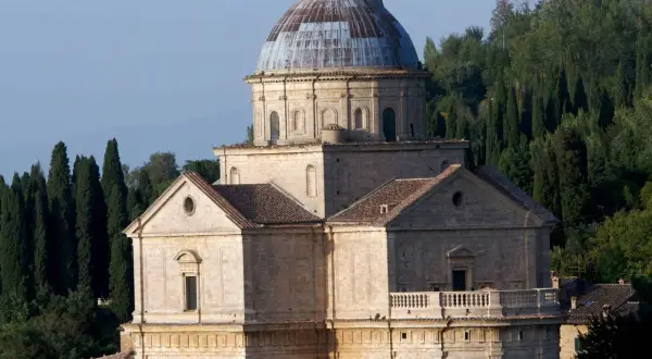 Il tempio di San Biagio, con la sua imponente cupola e la facciata in pietra, si erge maestoso tra i cipressi toscani.